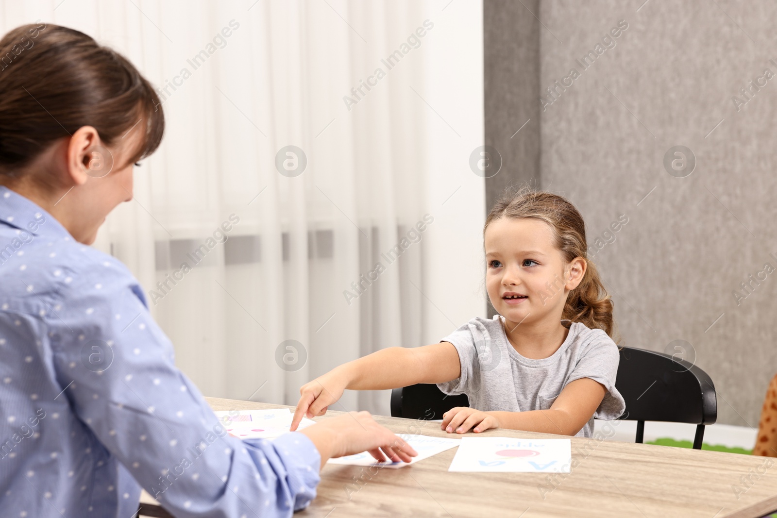 Photo of Smiling little girl with psychologist at autism therapy session