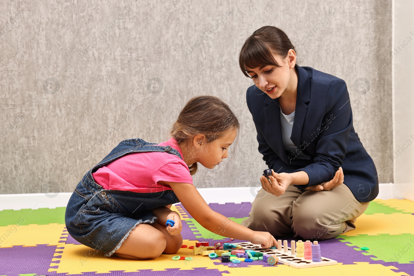 Photo of Autism therapy. Psychologist and little girl playing with educational toy in mental health center