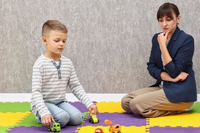 Photo of Psychologist observing little boy playing in autism treatment center