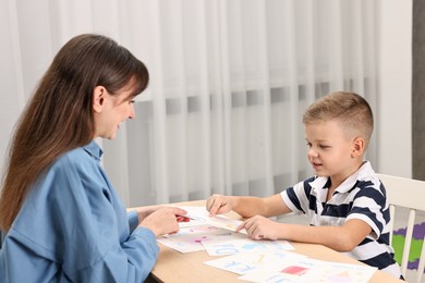 Photo of Speech therapist working with little boy at table in autism treatment center