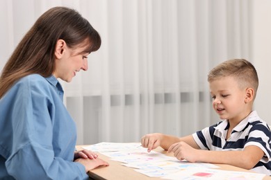 Speech therapist working with little boy at table in autism treatment center