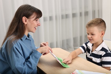 Photo of Smiling psychologist working with little boy in autism treatment center