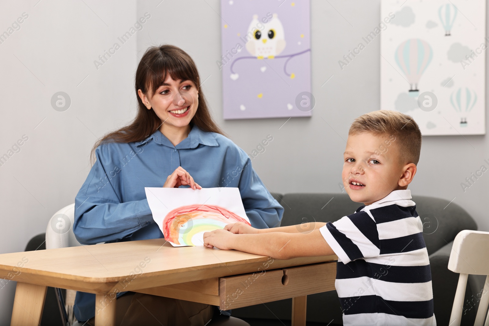 Photo of Smiling psychologist working with little boy in autism treatment center