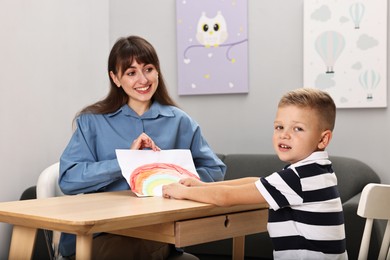 Smiling psychologist working with little boy in autism treatment center