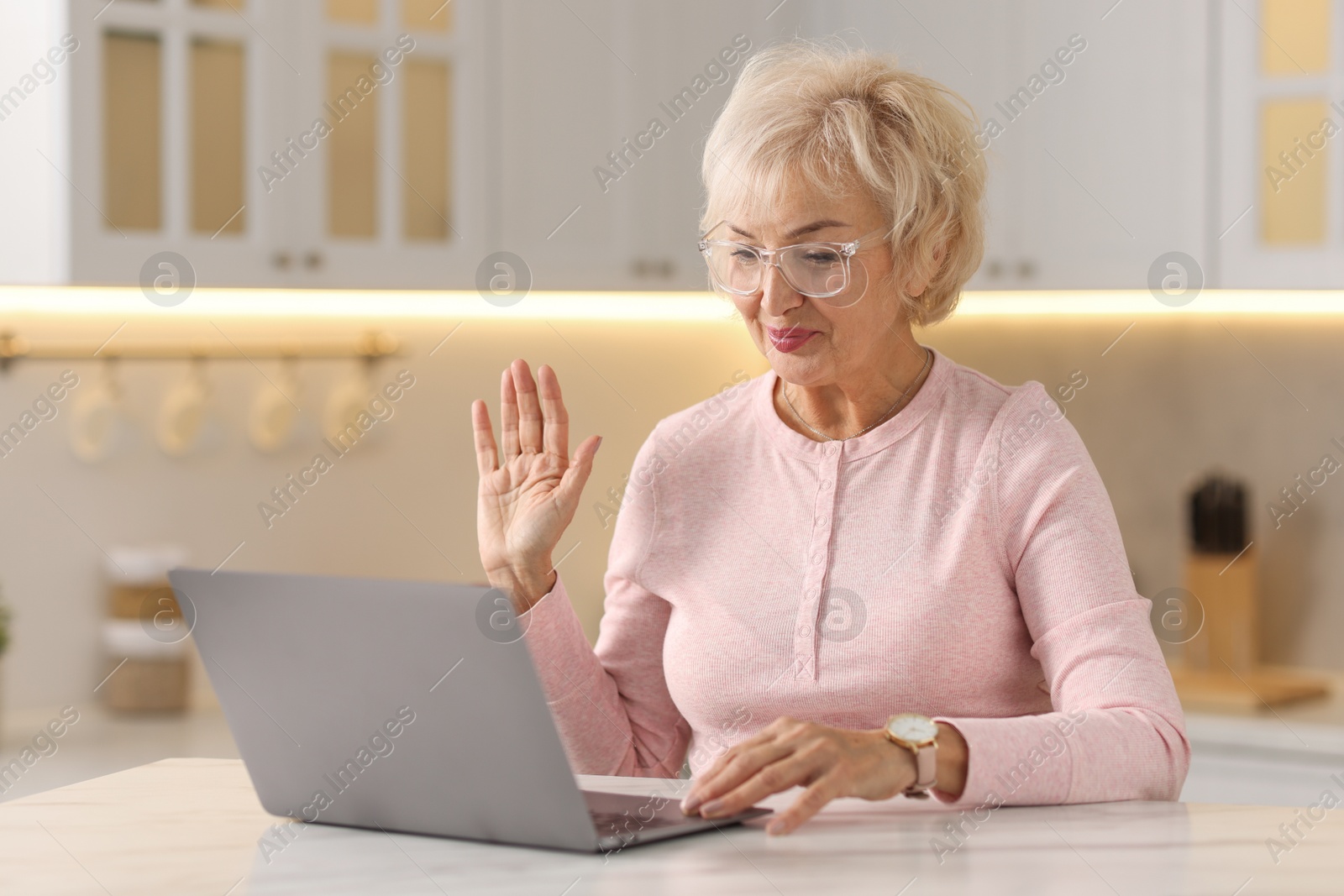 Photo of Beautiful grandmother having video chat via laptop in kitchen