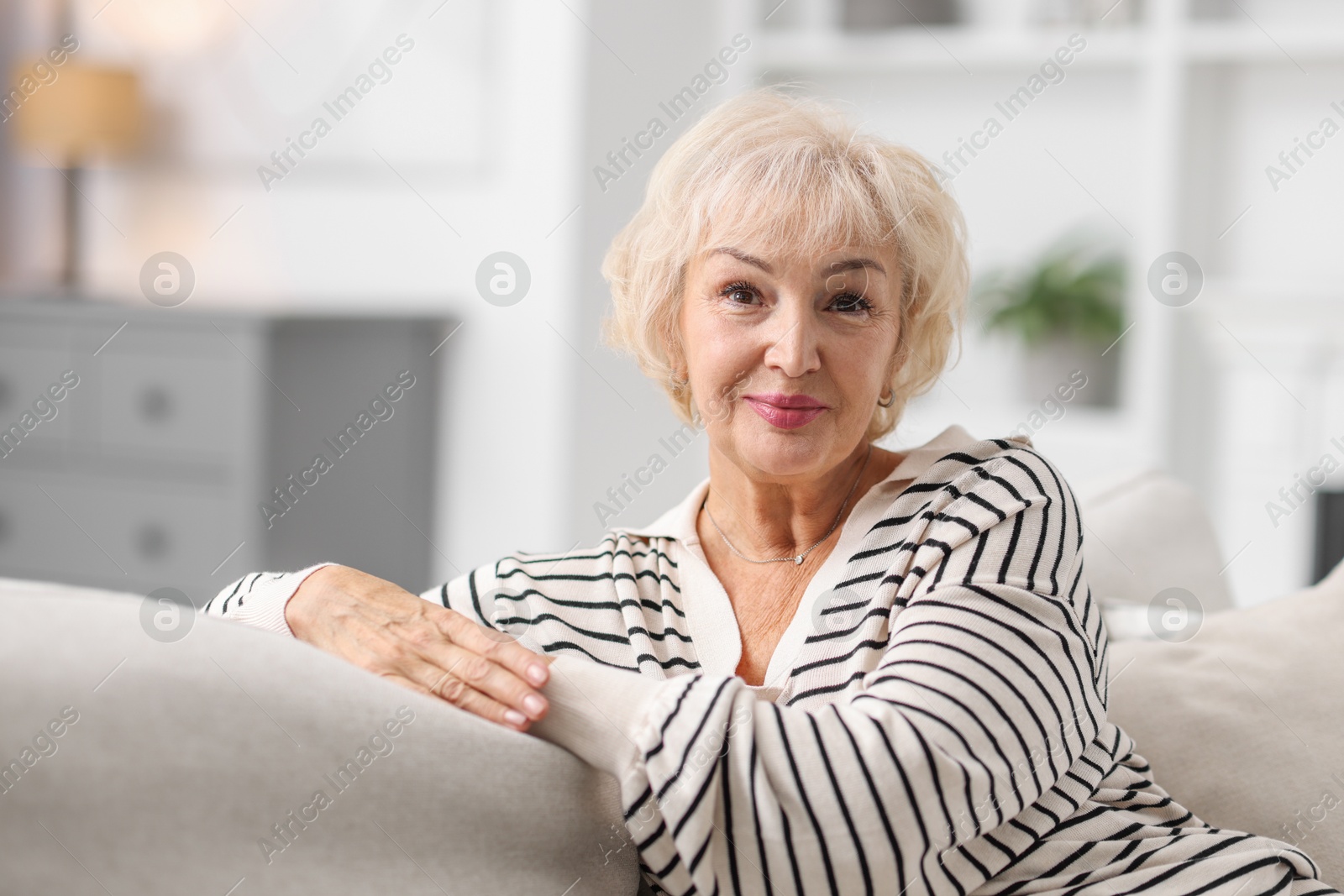 Photo of Beautiful grandmother sitting on sofa at home