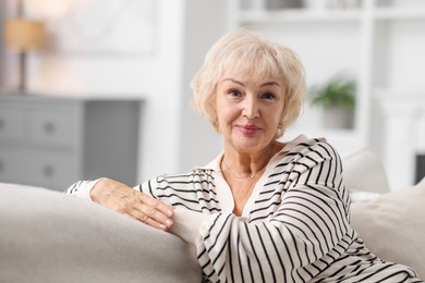 Beautiful grandmother sitting on sofa at home