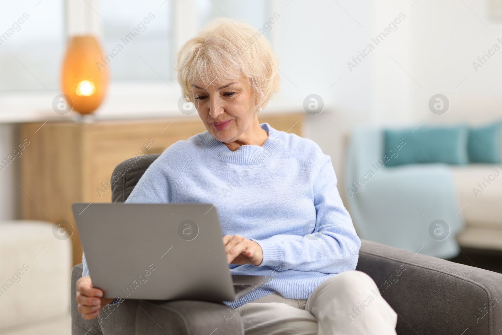 Photo of Portrait of beautiful grandmother using laptop at home