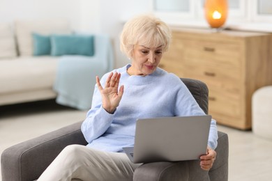 Photo of Beautiful grandmother having video chat via laptop at home