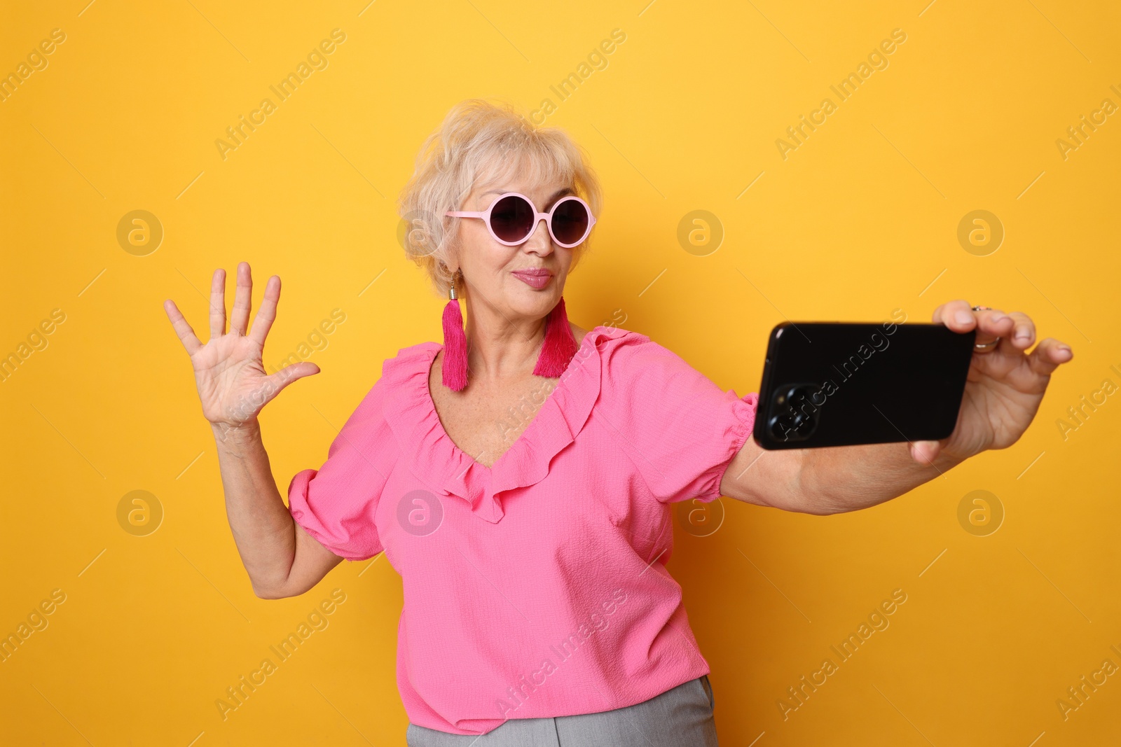 Photo of Cool grandmother taking selfie on orange background