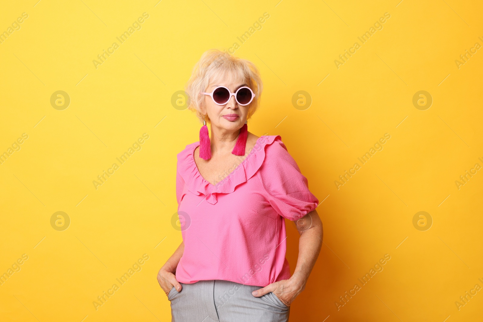 Photo of Portrait of fashionable grandmother in sunglasses on orange background