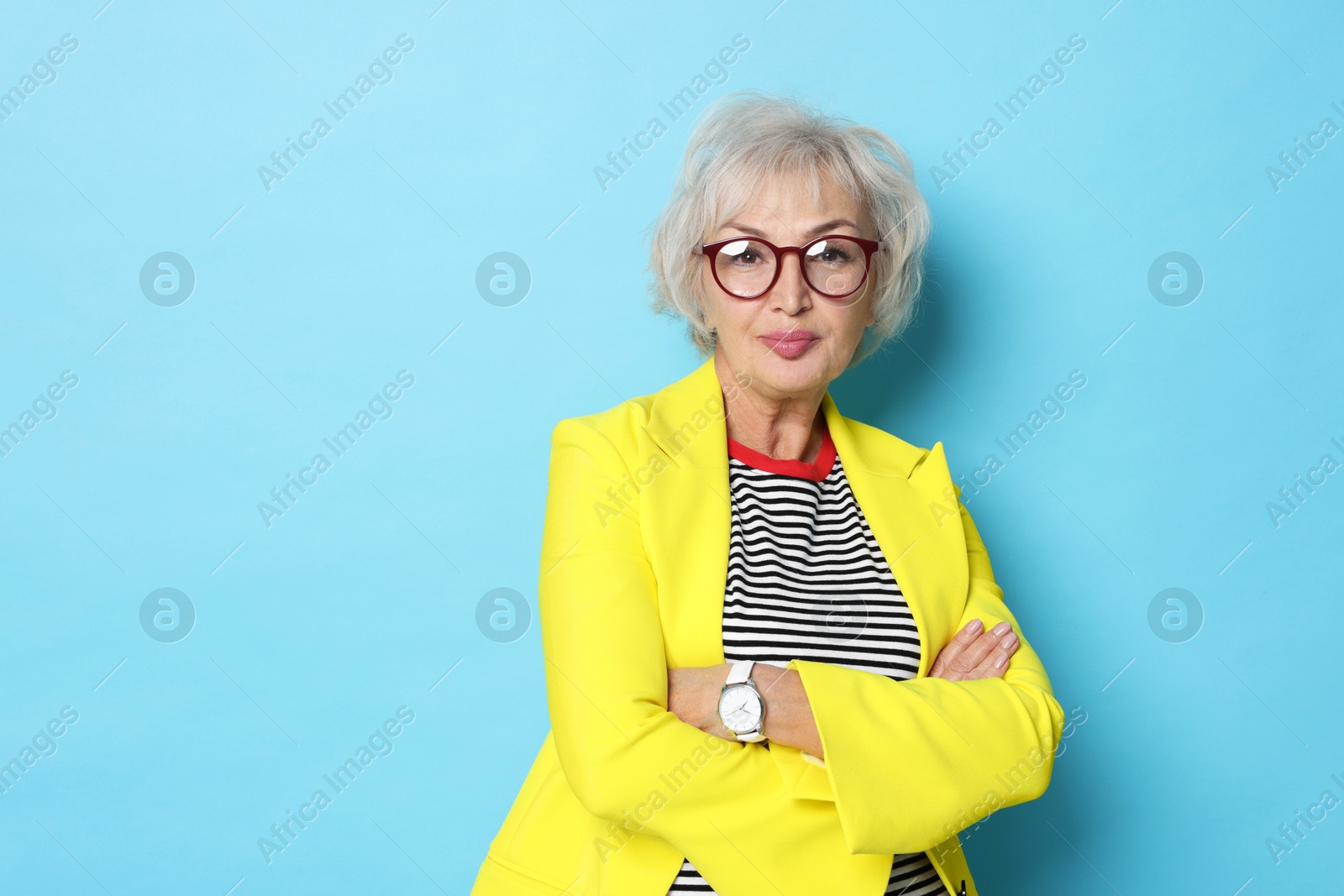 Photo of Portrait of grandmother in stylish yellow jacket on light blue background. Space for text