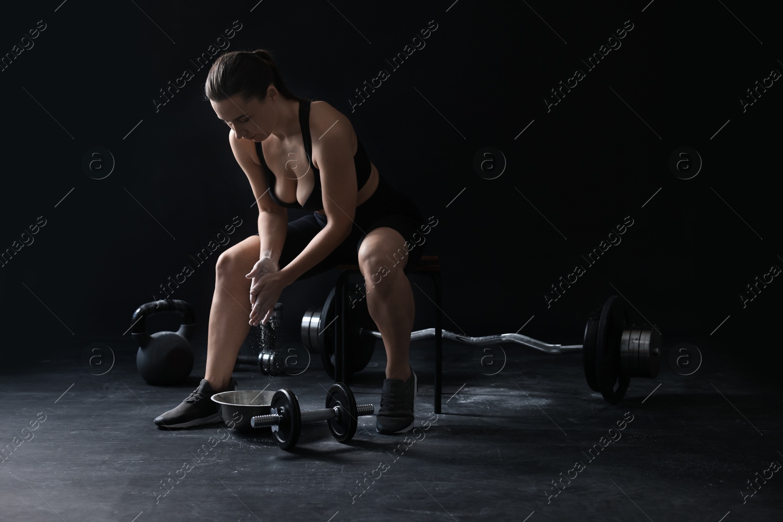 Photo of Woman applying talcum powder onto hands before training on black background