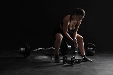 Photo of Woman applying talcum powder onto hands before training on black background