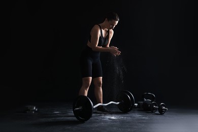 Photo of Woman applying talcum powder onto hands before training on black background