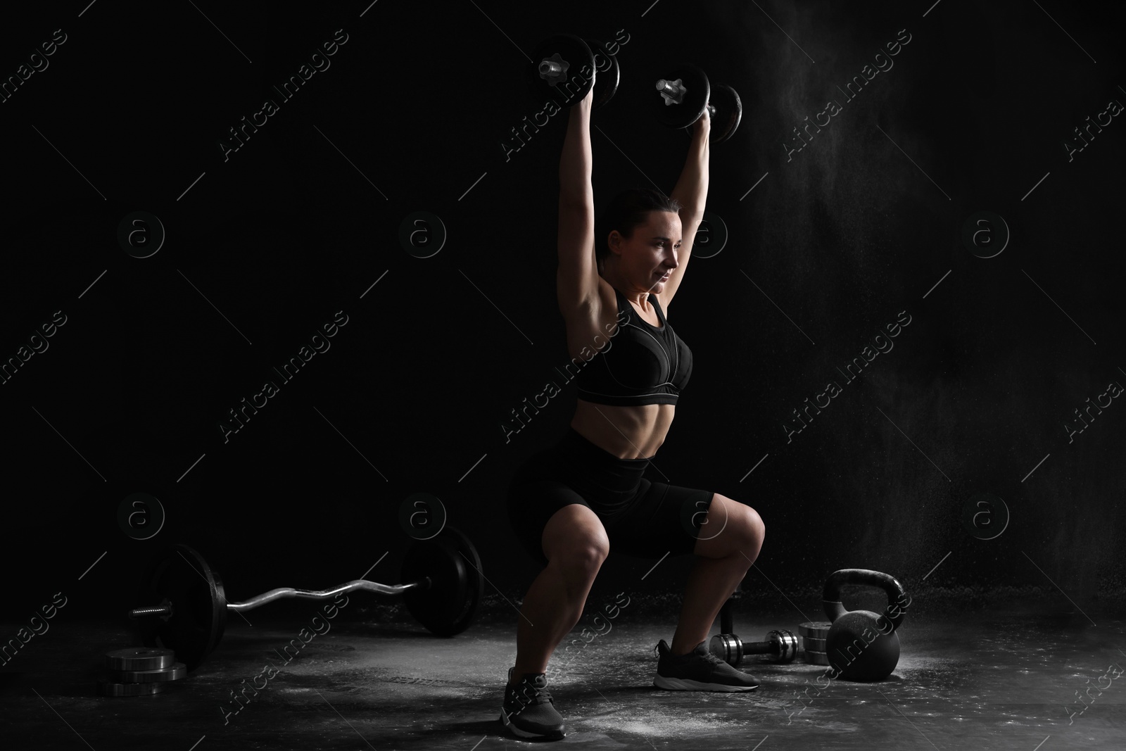 Photo of Woman training with barbells on black background, space for text