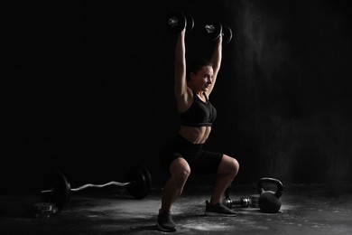 Woman training with barbells on black background, space for text