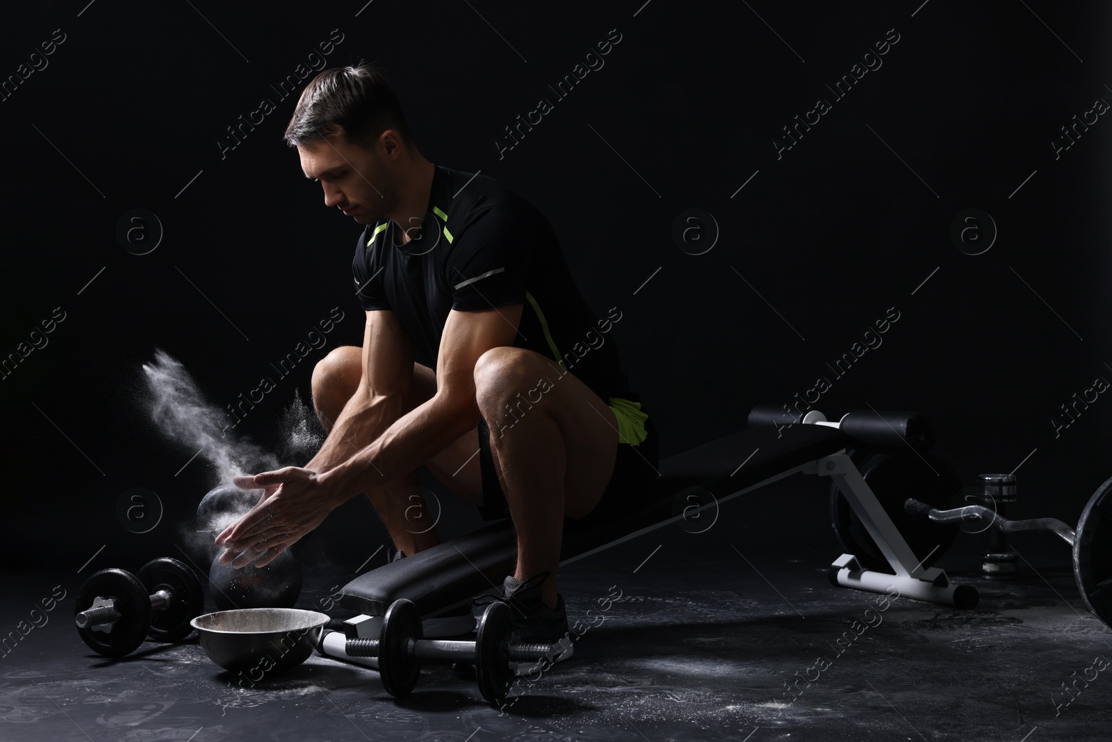 Photo of Man clapping hands with talcum powder before training on black background