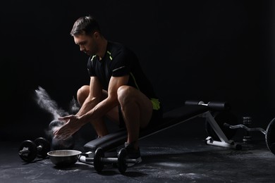 Photo of Man clapping hands with talcum powder before training on black background