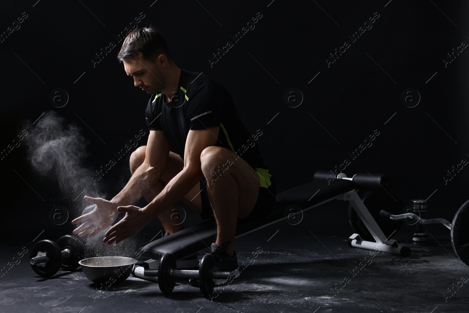 Photo of Man clapping hands with talcum powder before training on black background