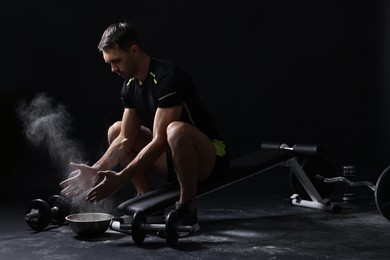 Photo of Man clapping hands with talcum powder before training on black background