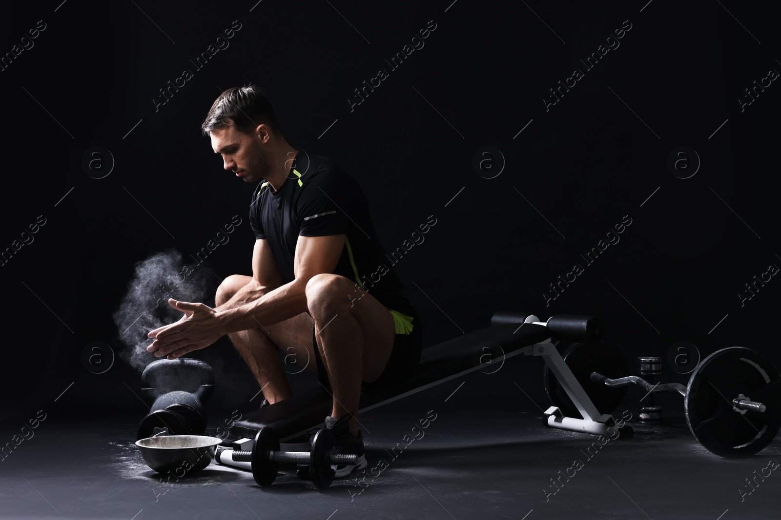 Photo of Man clapping hands with talcum powder before training on black background