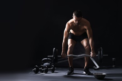 Photo of Man training with barbell against black background