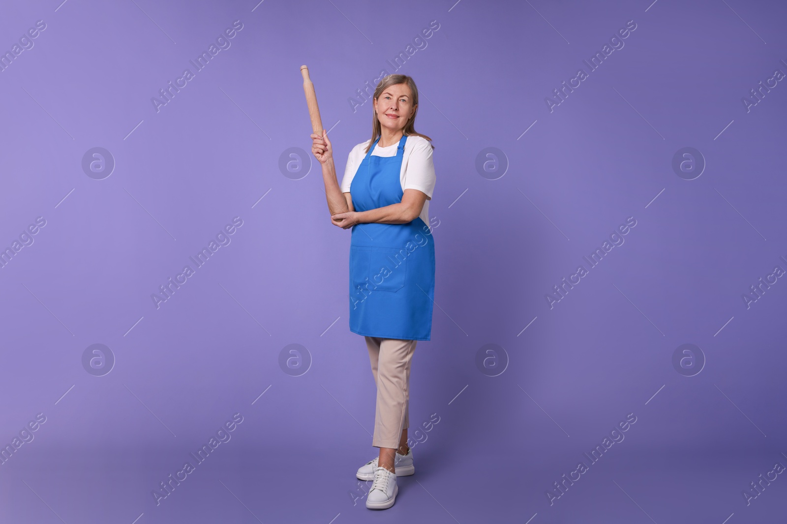 Photo of Woman with rolling pin on violet background