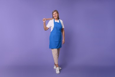 Happy woman with rolling pin on violet background