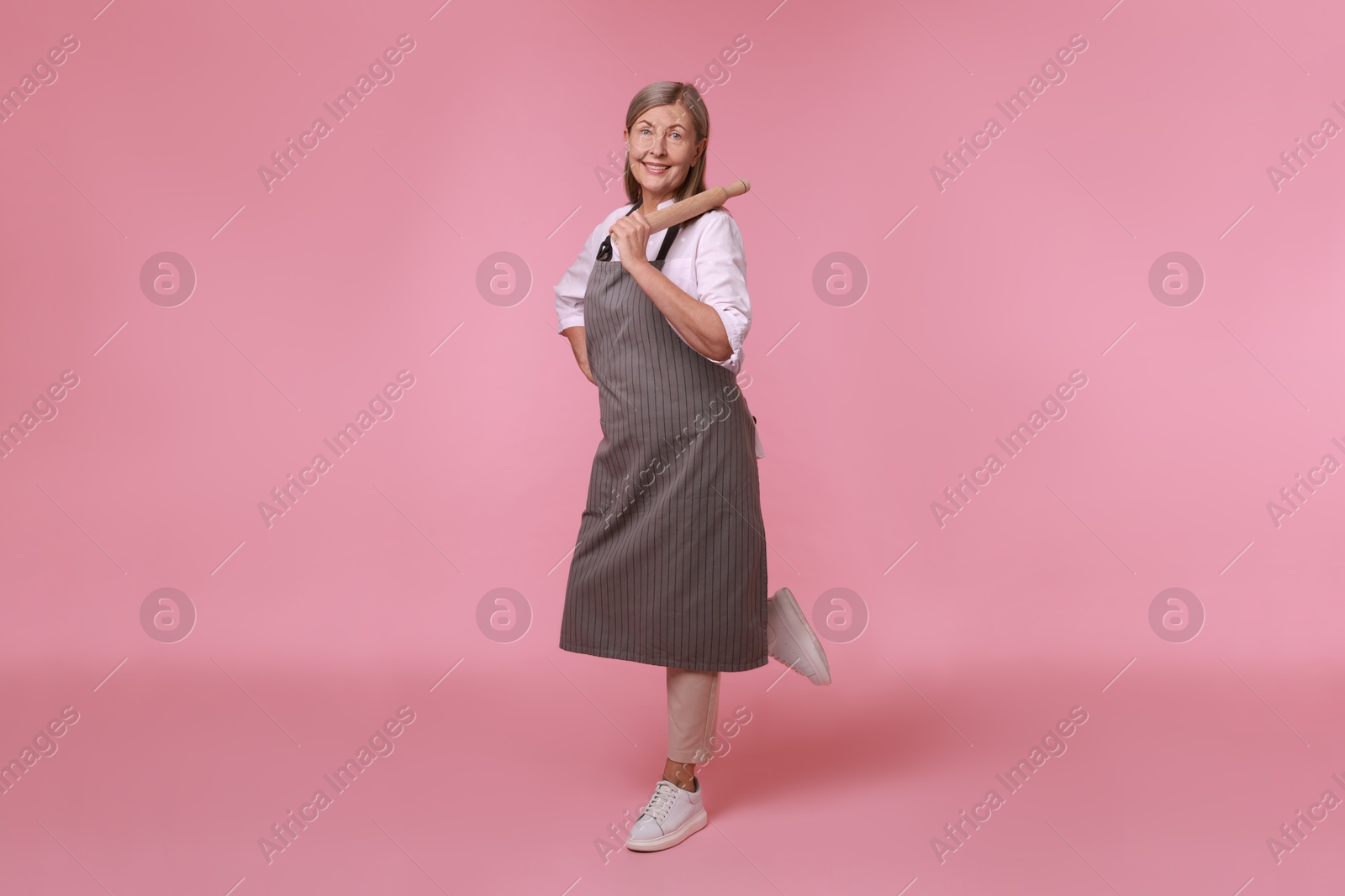 Photo of Happy woman with rolling pin on pink background