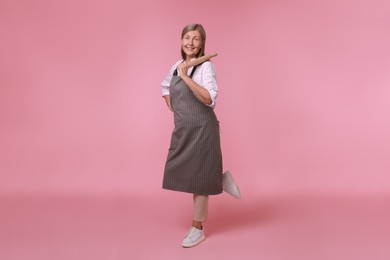 Happy woman with rolling pin on pink background