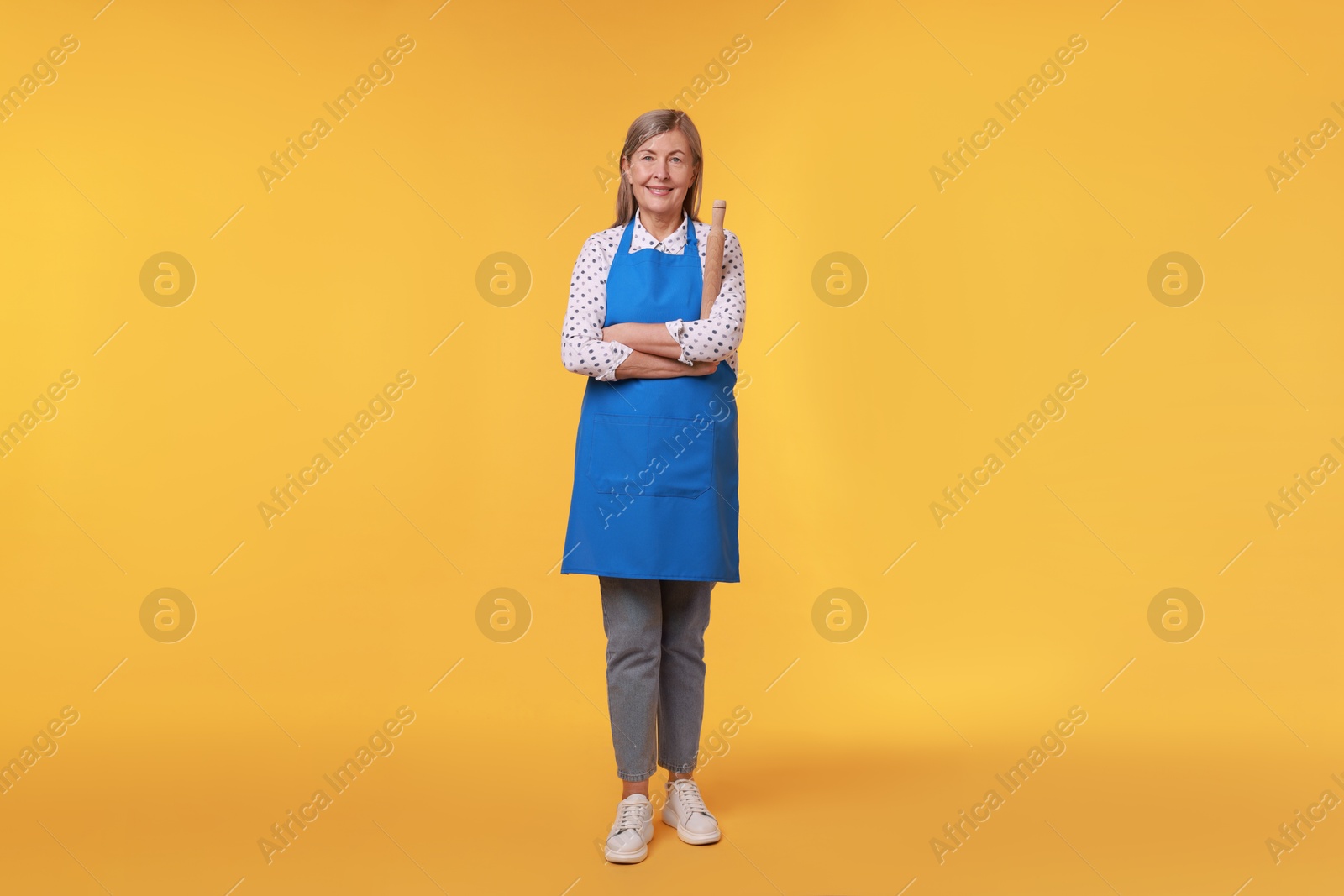 Photo of Happy woman with rolling pin on yellow background