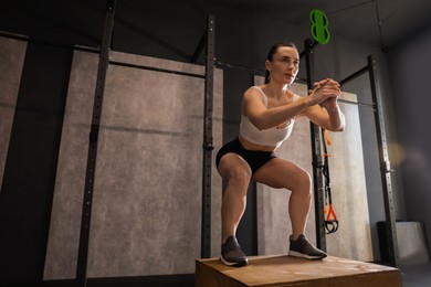 Sportswoman doing squat during crossfit workout in gym. Space for text