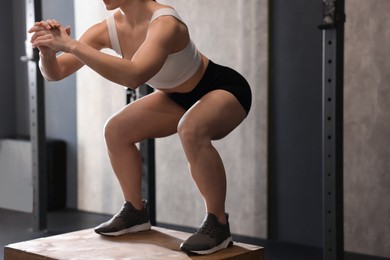 Sportswoman doing squat during crossfit workout in gym, closeup. Space for text