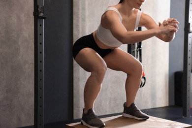 Sportswoman doing squat during crossfit workout in gym, closeup. Space for text