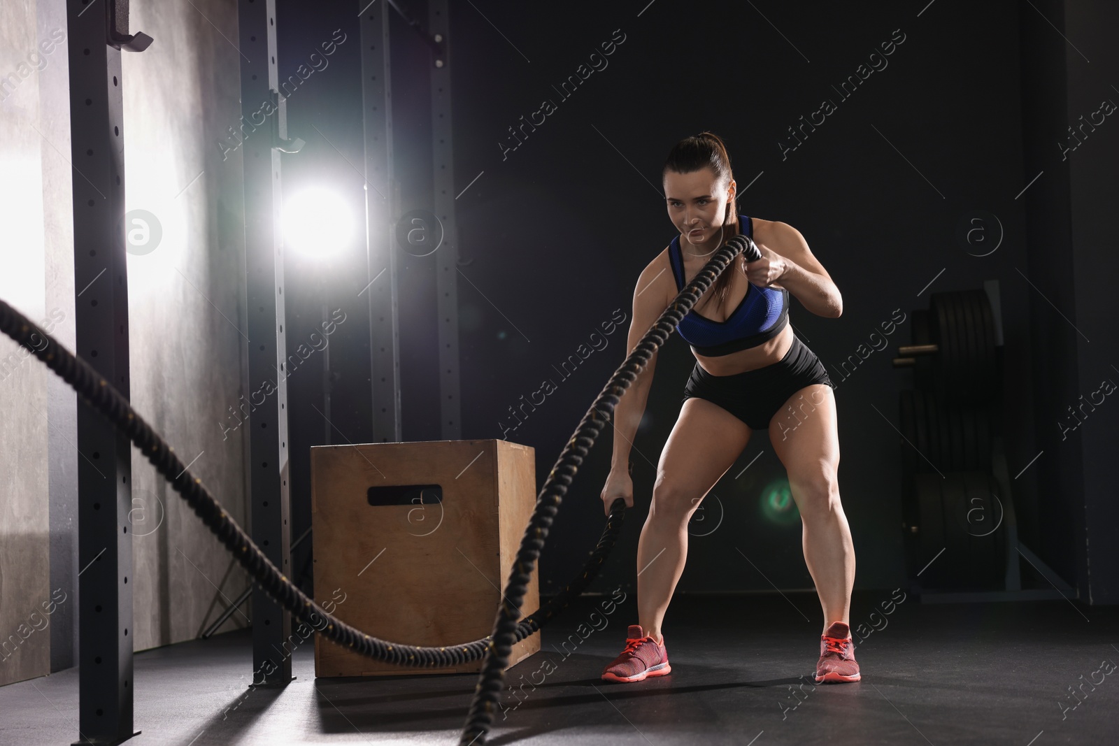 Photo of Sportswoman exercising with battle ropes during crossfit workout in gym