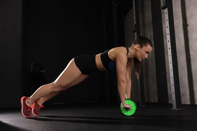 Photo of Sportswoman exercising with ab wheel during crossfit workout in gym