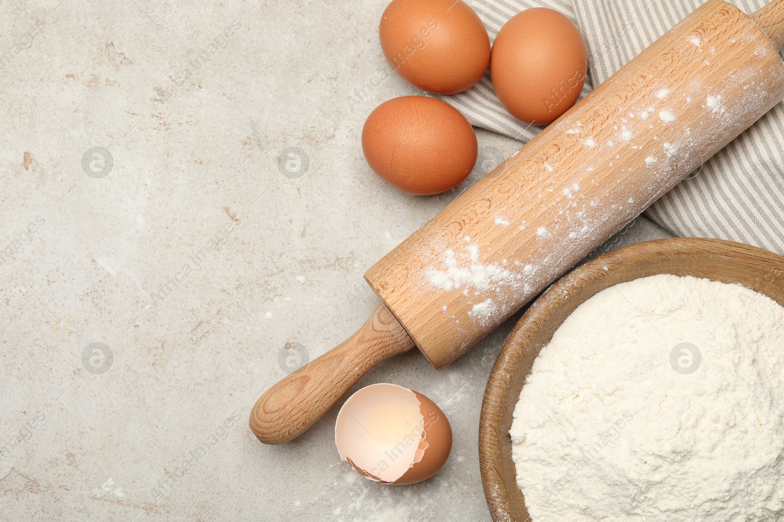 Rolling pin, flour and eggs on light grey background, flat lay. Space for text Photo of Rolling pin, flour and eggs on light grey background, flat lay. Space for text