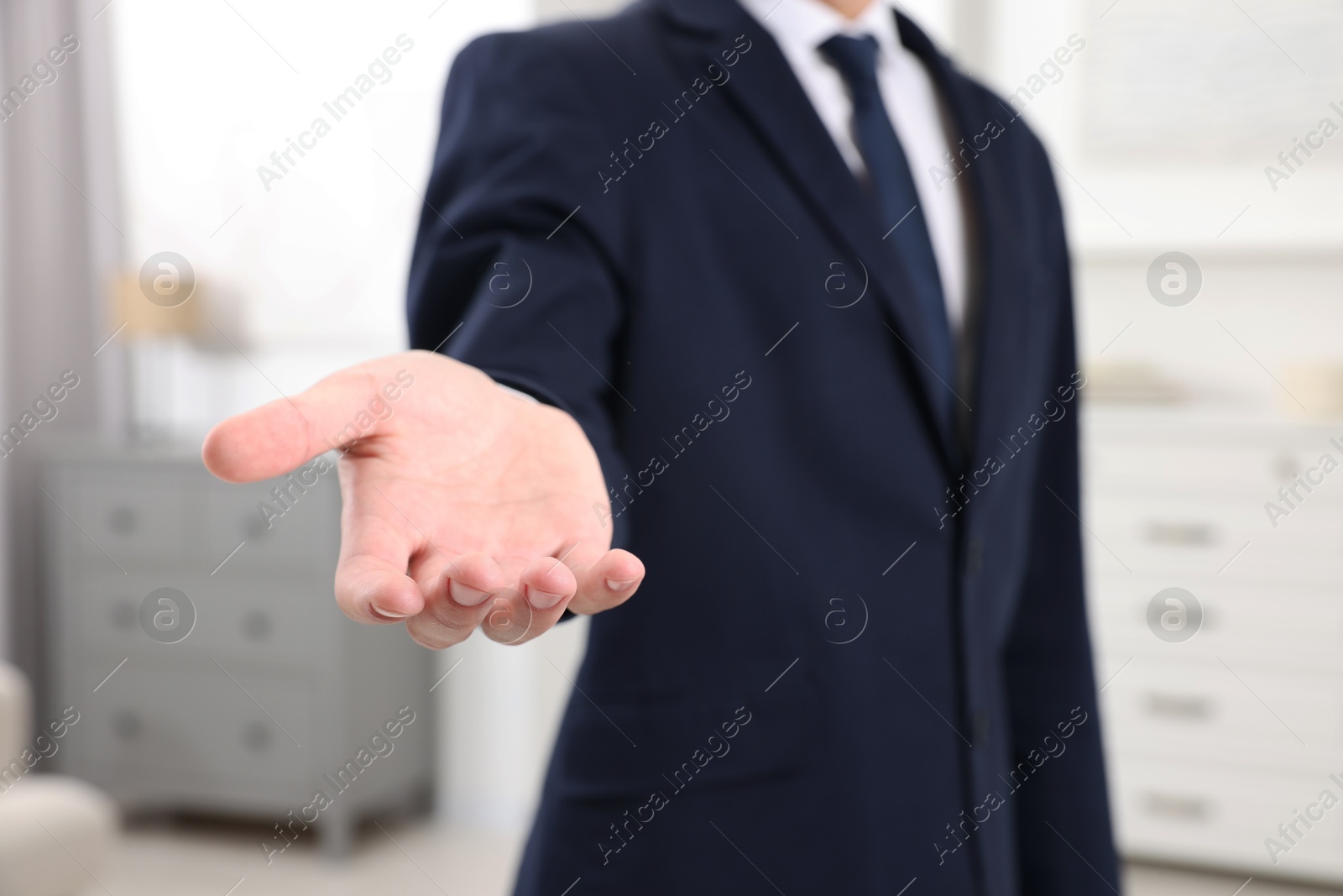 Photo of Offering help. Man reaching his hand indoors, closeup