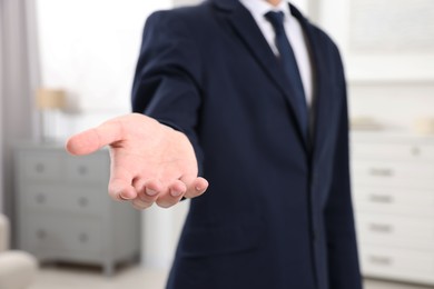 Photo of Offering help. Man reaching his hand indoors, closeup