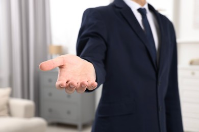 Photo of Offering help. Man reaching his hand indoors, closeup