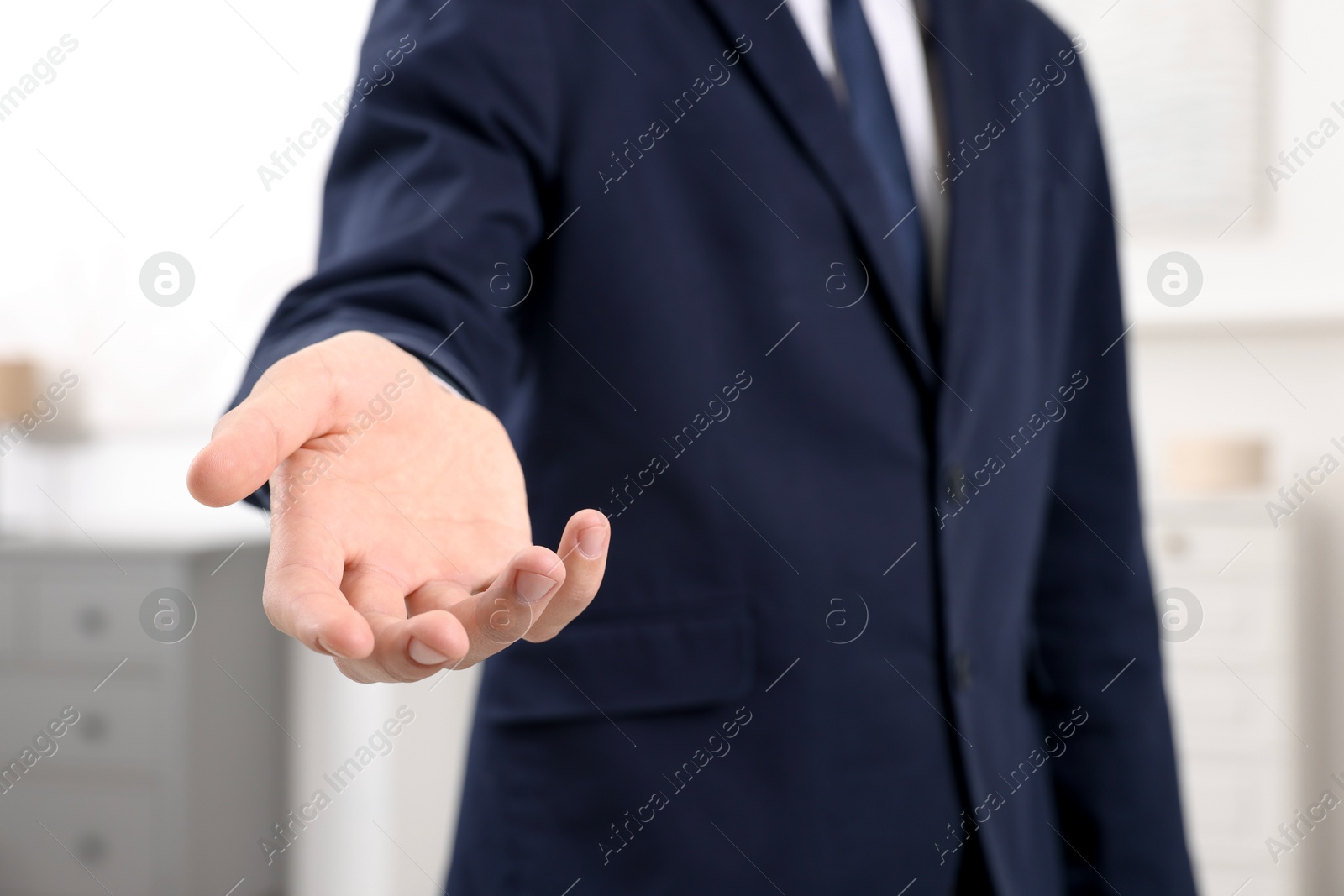 Photo of Offering help. Man reaching his hand indoors, closeup