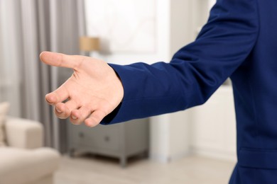 Photo of Offering help. Man reaching his hand indoors, closeup