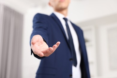 Photo of Offering help. Man reaching his hand indoors, closeup