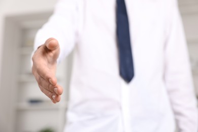 Photo of Offering help. Man reaching his hand indoors, closeup