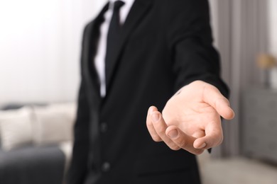 Photo of Offering help. Man reaching his hand indoors, closeup