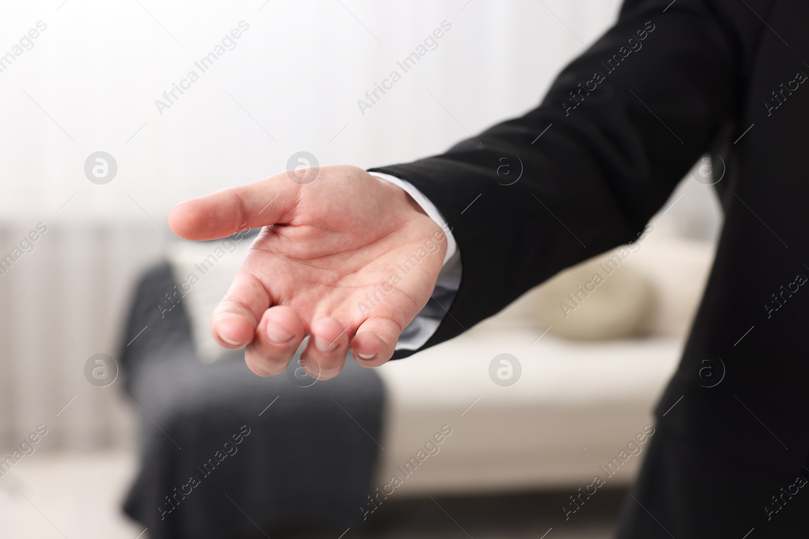 Photo of Offering help. Man reaching his hand indoors, closeup