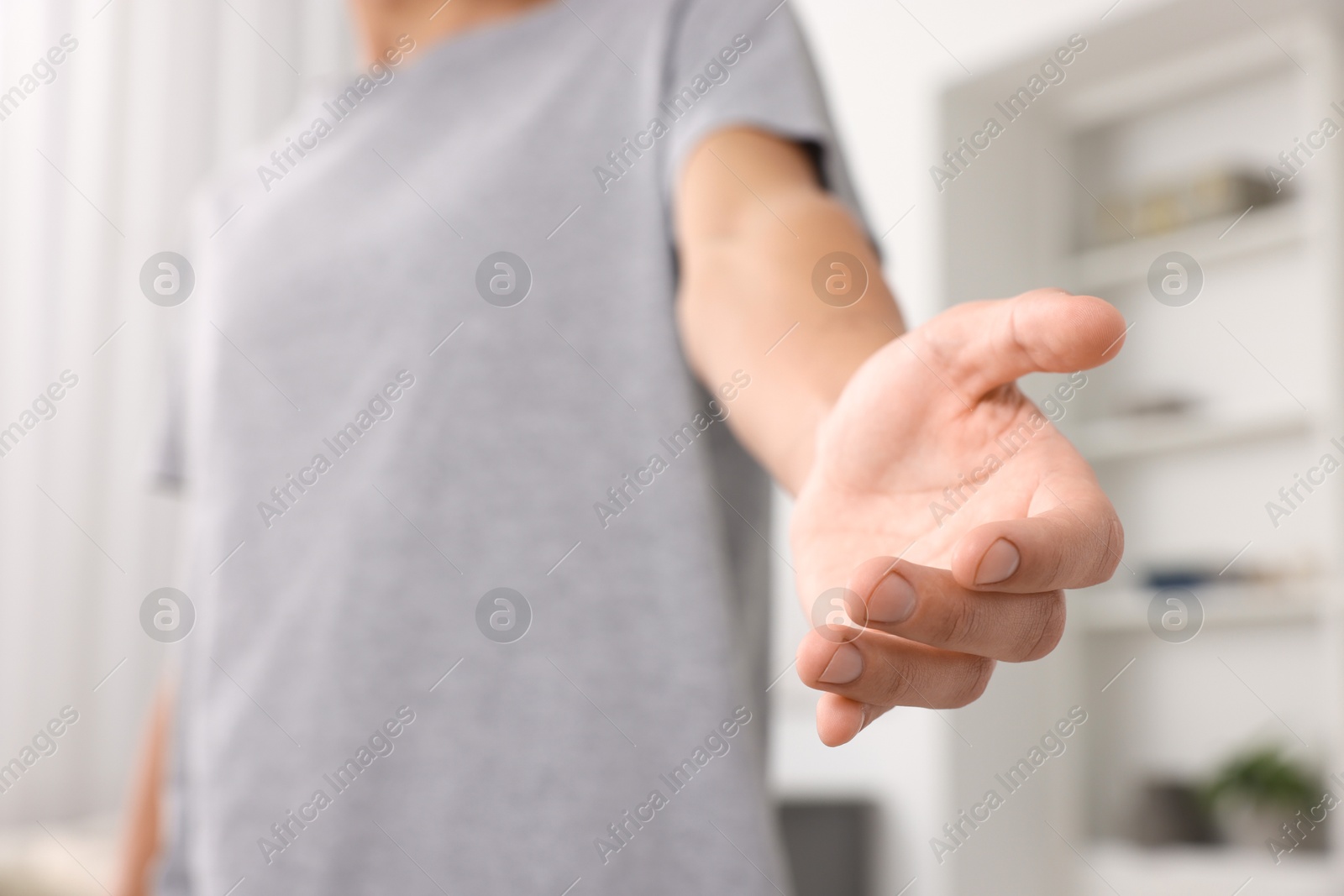 Photo of Offering help. Man reaching his hand indoors, closeup