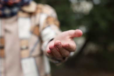 Photo of Offering help. Man reaching his hand outdoors, closeup