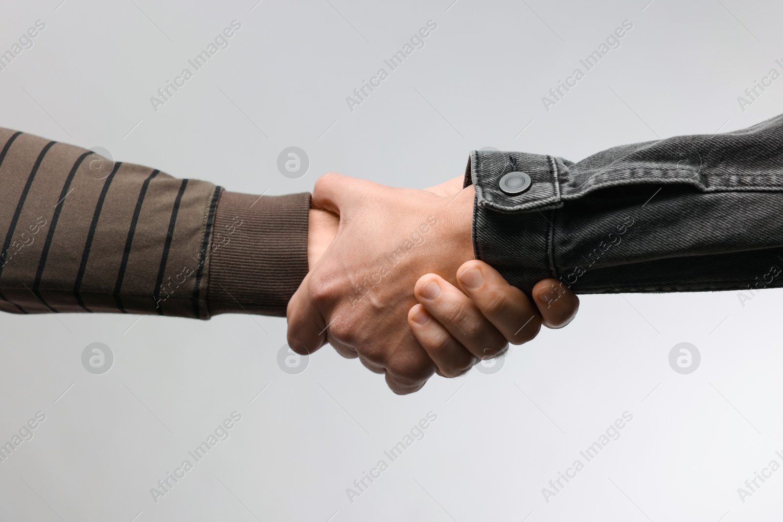 Photo of Help and support. People holding hands on light grey background, closeup